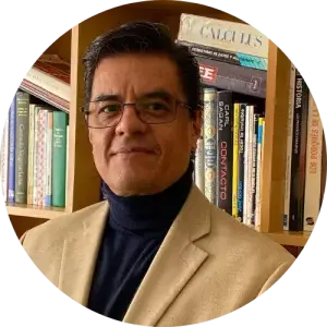 Luis Antonio Nieto, with tan blazer, black turtleneck in front of bookcase.