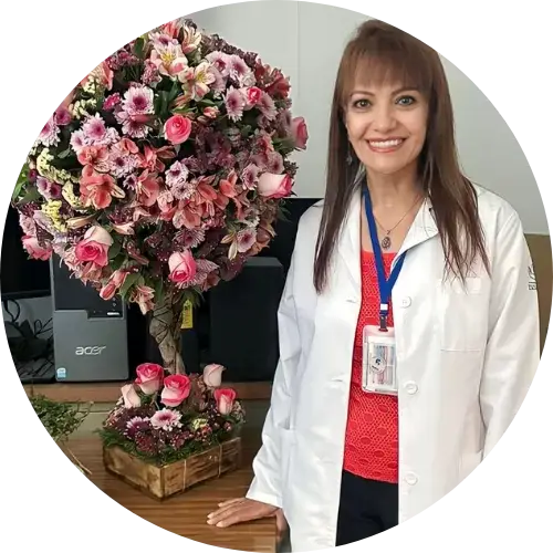 Dr. Rosy Garcia, standing, wearing a white lab coat, next to a beautiful floral arrangement.